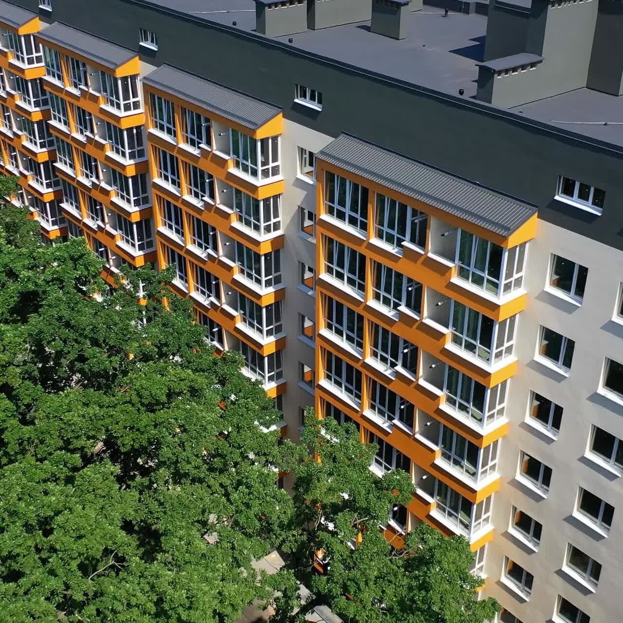 Exterior of a modern high rise building. New apartment building of contemporary design with large windows and balconies near green trees