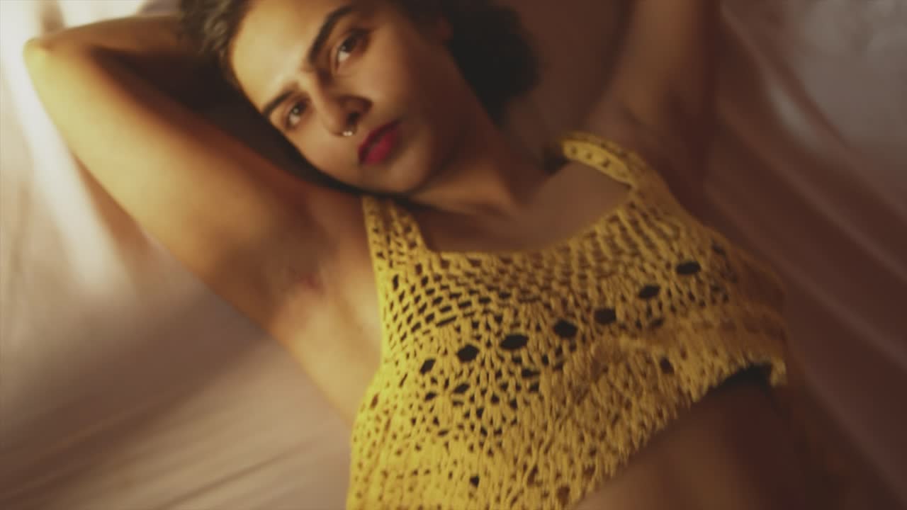 Exotic woman lying on bed, seductive cinematic zoom of flirt girl with red lips