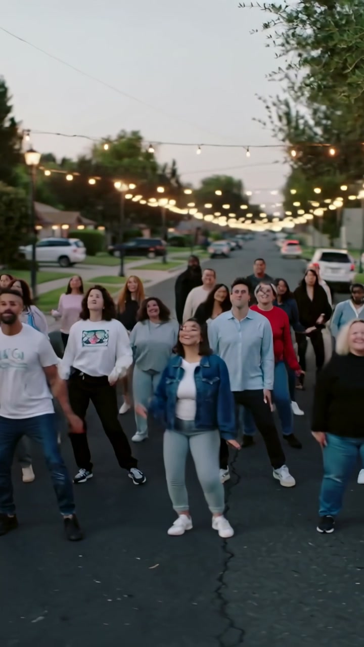 Vertical video: Stepping man white tee and woman denim jacket leading group rehearsing under bulbs