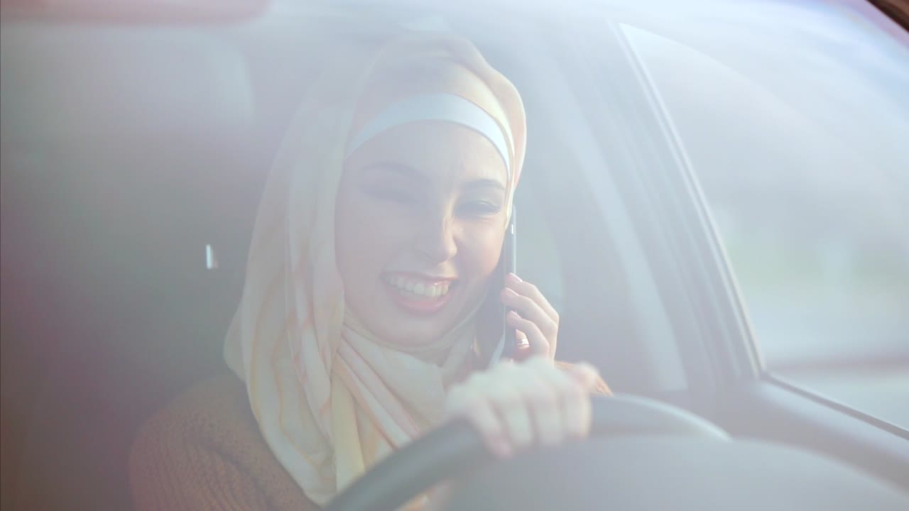 Woman in Hijab Driving and Talking on Phone