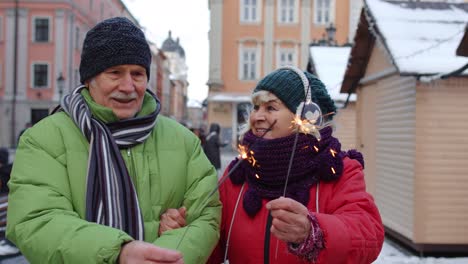 elderly family holding bengal lights enjoying christmas eve, celebrating birthday on city street