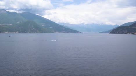 speedboat chasing over lake como surrounded by cloud-covered mountains