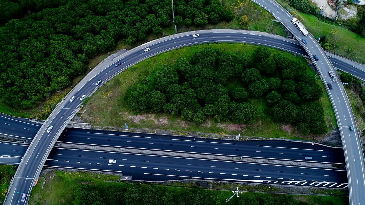 프랑스의 고속도로 교차로 위의 공중 전망 - 도로 주변의 집과 풀, 도로에서 운전하는 자동차와 트럭