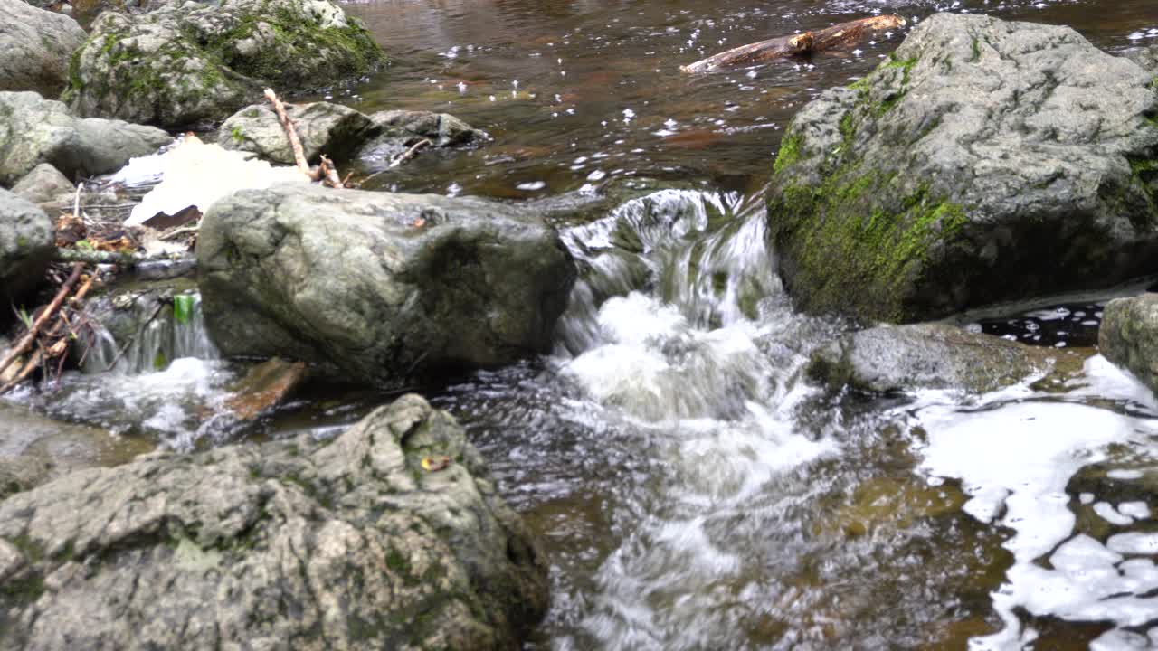A quiet stream of water is flowing on the rocks that creating a scene of relation for the mind