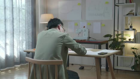 남자 가방 디자이너의 뒷면은 사무실에서 레이아웃 본드를 그리고 있습니다.