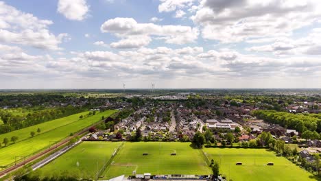 aerial view of a dutch town with wind turbines and soccer field