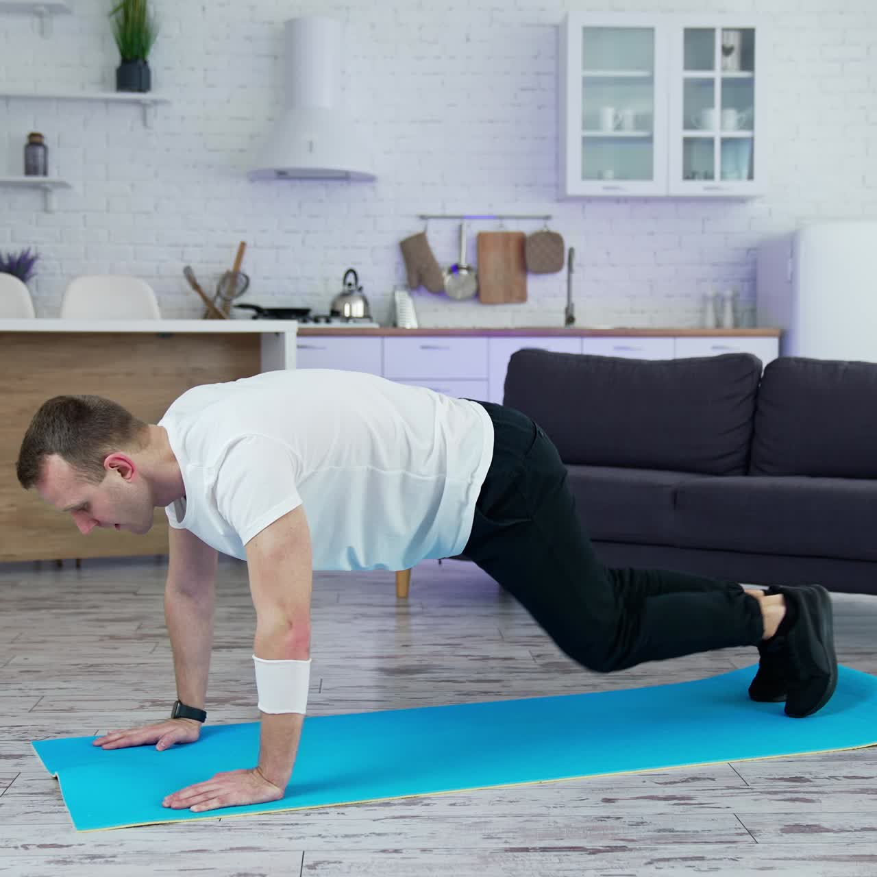 Sportsman exercising in the kitchen. Young man doing fitness exercises on a mat at home during lockdown. Wellness and healthy lifestyle