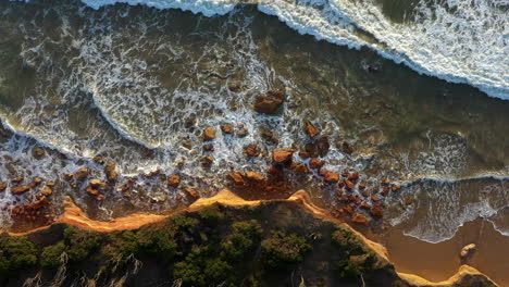 aerial directly above limestone cliff, waves crashing, coastal erosion