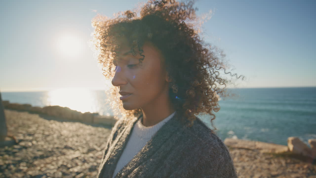 Primo piano di una ragazza turbata che guarda in lontananza sulla spiaggia. Volto di donna triste con i capelli mossi dal vento.