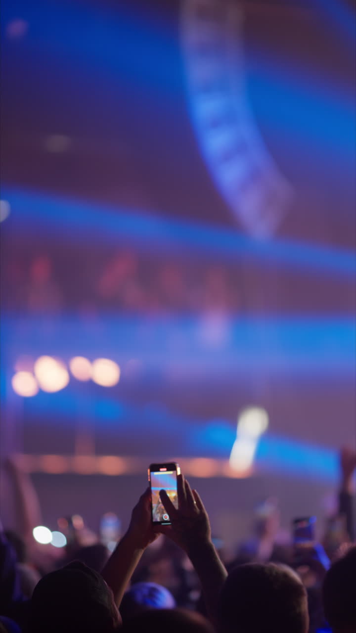 Persona che registra un concerto dal vivo con uno smartphone in un locale buio