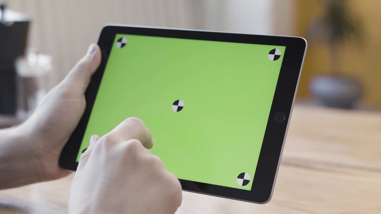 녹색 화면을 가진 태블릿을 사용하는 사람