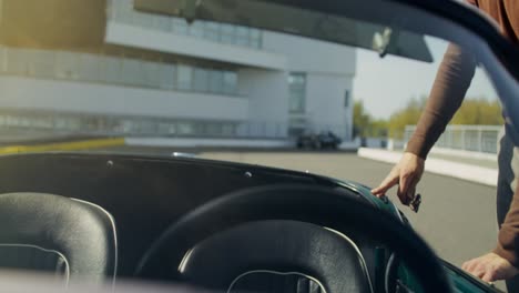 man driving a vintage sports car on a racetrack