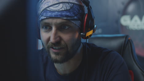 a focused gamer wearing a bandana and headphones playing or streaming