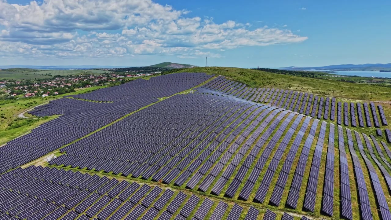 Solpaneler dækker land nær et landområde under en klar blå himmel