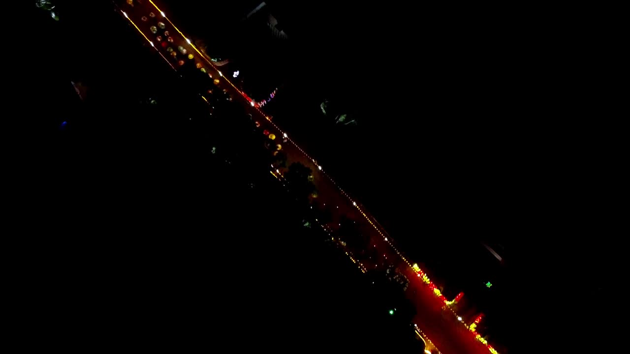 Veduta aerea notturna di un vivace ponte cittadino illuminato da luci dorate, che mostra il traffico scorrevole e l'architettura urbana festosa da una prospettiva aerea con drone