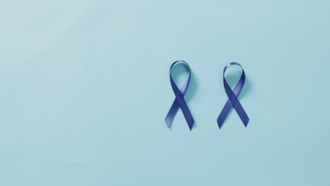 video of two dark blue colon cancer ribbons on pale blue background