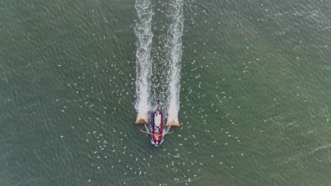 drone topdown shot of a fishers boat dragging the nets thru the water