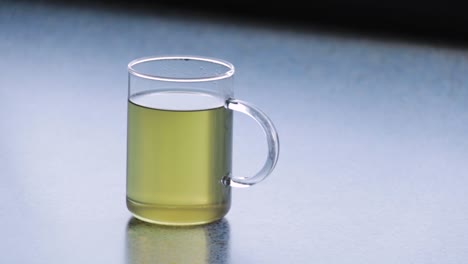 vista de esquina de una taza de vidrio caliente de té verde en una superficie limpia