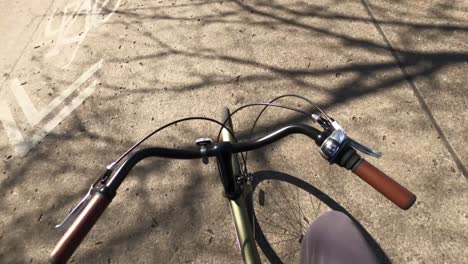 first person point of view of man riding green bicycle with shadows on street