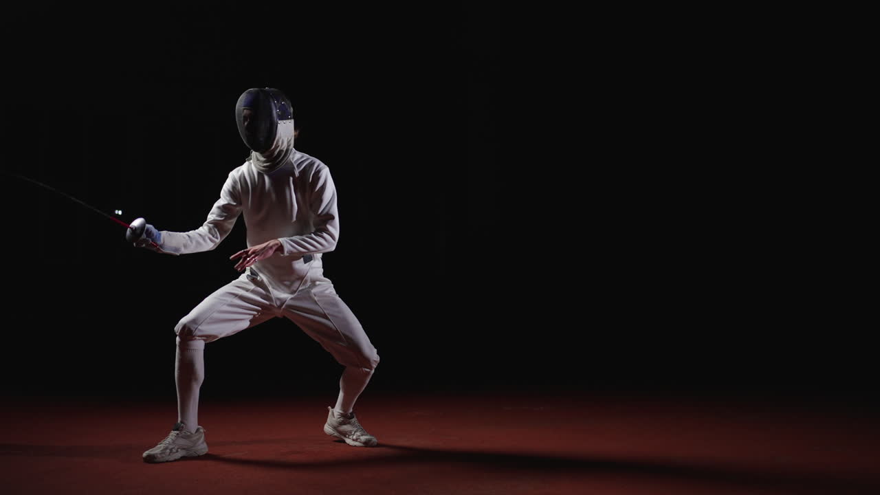 A fencer in white uniform with sword in hand, standing on a red floor against a black background.