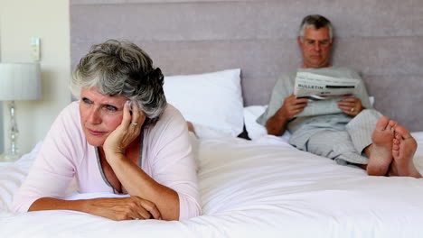 woman worried about something while her husband is reading newspapers