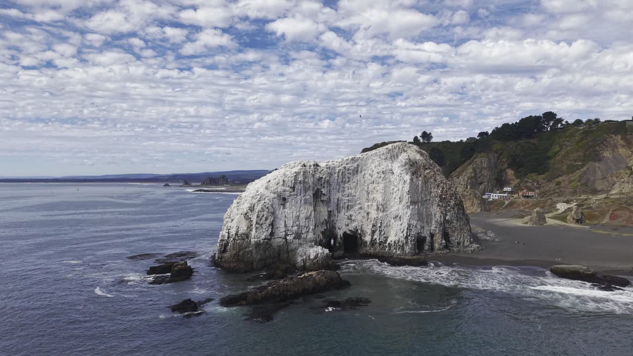 Orbita intorno a Piedra del Elefante, rivelando grotte marine e onde su una spiaggia di sabbia nera vicino a Constitución Maule, Cile, 4K.
