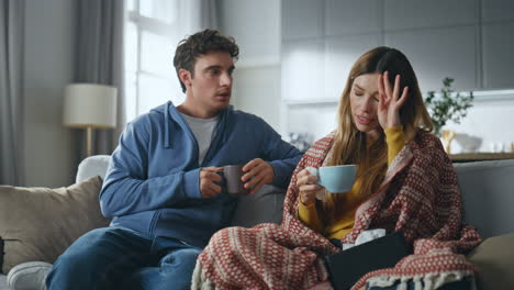 affectionate man caring sick girlfriend at living room. lady drinking beverage