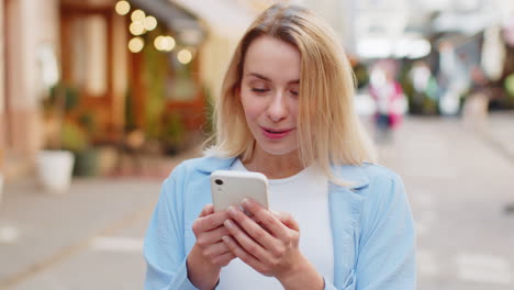 excited happy winner woman use smartphone looking amazed at screen celebrating win good message news