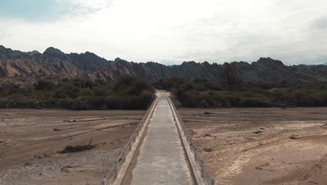 vuelo de avión no tripulado sobre un puente estrecho que cruza el río cachalqui en las quebradas de las flechas, provincia de salta, argentina