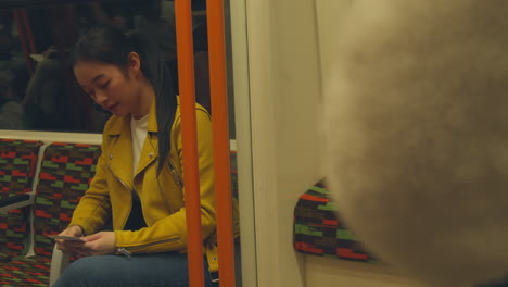 mujer sentada en el tren subterráneo mirando fotos tomadas con un amigo