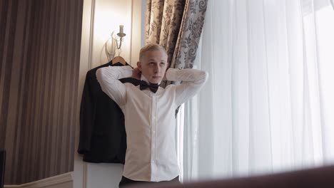 groom man adjusts bow tie, preparing to go to the bride, businessman in white shirt, wedding day