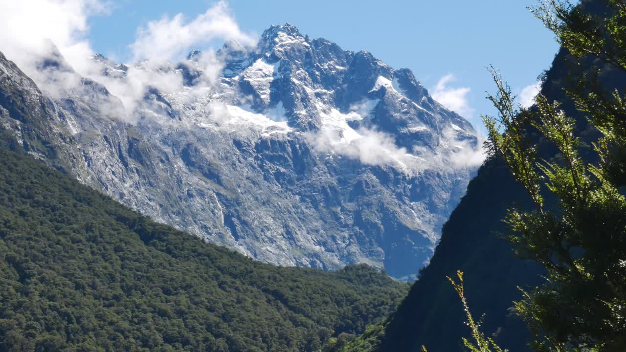 toma panorámica de hermosas montañas con iluminación de nieve por el sol y nubes flotantes en el aire