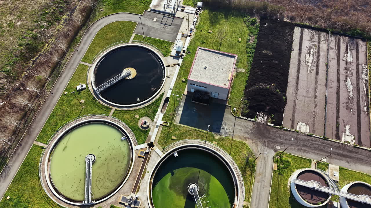 Water treatment facility operates with multiple tanks and processing units in an urban area during daylight hours