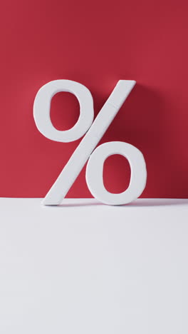 vertical video of white percent sign with copy space against red background