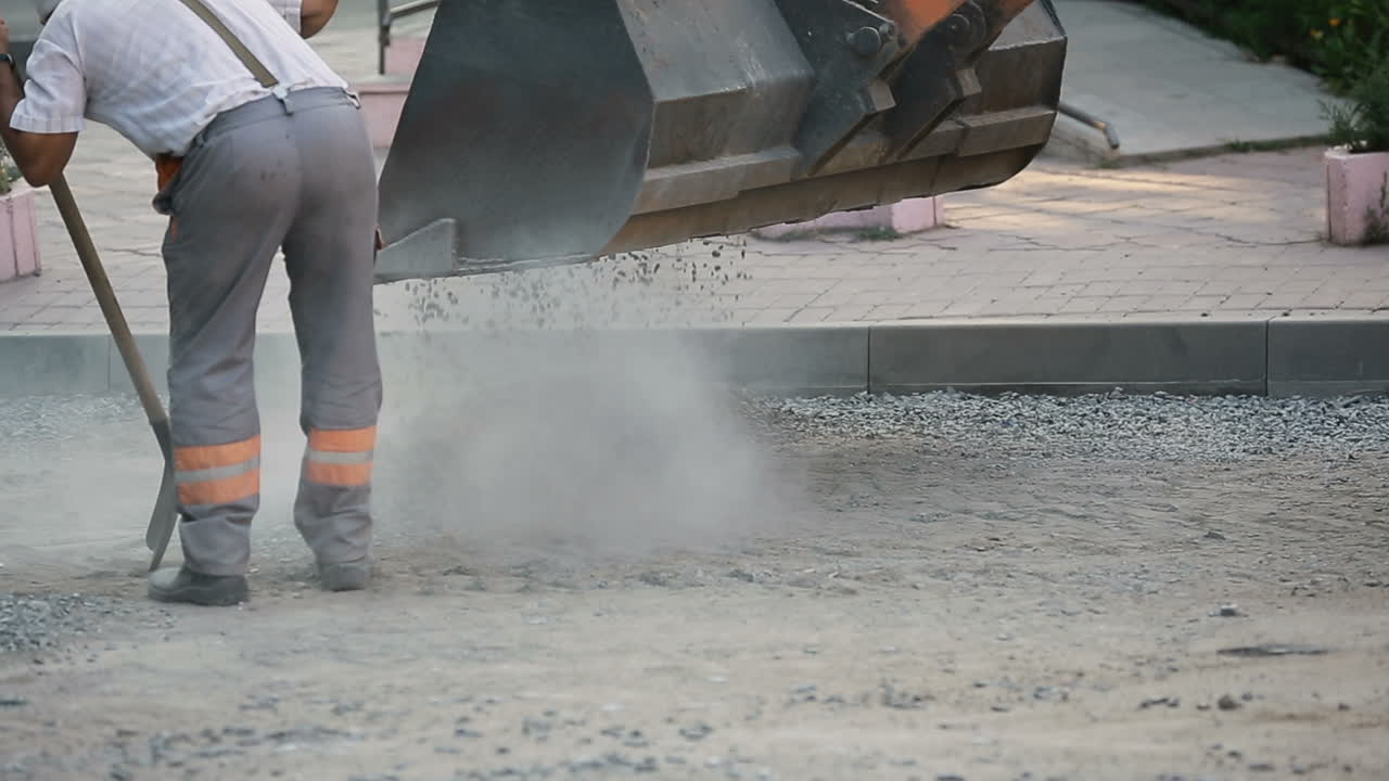 Road Workers Repair Work. Construction worker holding shovel with gravel working on road construction