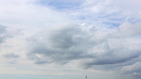 Calm-cloud-blanket-forming-and-small-cumulus-clouds-passing-by-with-a-blue-sky-and-sun-rays-in-the-background