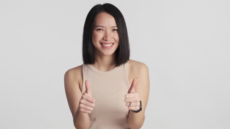 asian woman keeping thumbs up on camera.