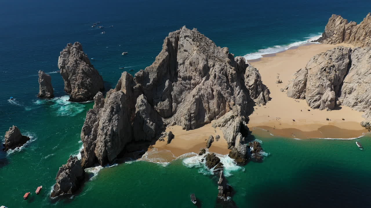 filmación cinematográfica con drones de acantilados marinos con playa del amor y el arco a la vista en cabo san lucas méxico, descendiendo lentamente