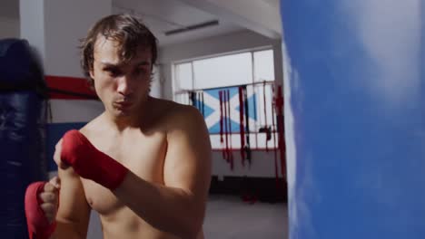 Caucasian-man-using-punchbag-in-boxing-gym