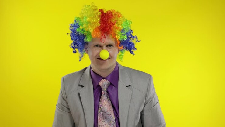 Uomo d'affari clown, imprenditore capo con parrucca, agita le mani. Sfondo giallo