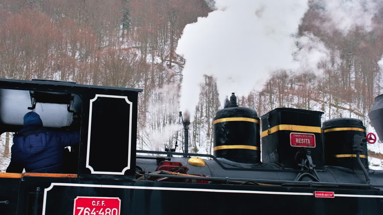 View of the wound-up steam train Mocanita on a railway station in winter, snow, bare forest around, Romania