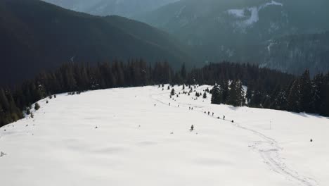 Snowy-mountain-landscape-in-Iezer-Papusa,-Romania-with-hikers,-trees,-and-trails