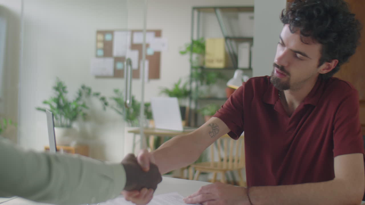 Young Businessman Shaking Hands with Coworker in Office
