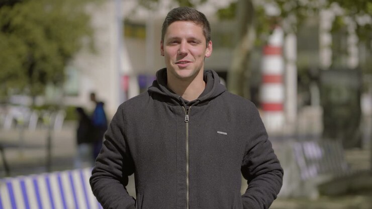 Bell'uomo giovane che parla alla telecamera all'aperto.