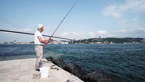 fisherman fishing at bosporus strait with view of famous bridge landmark at background