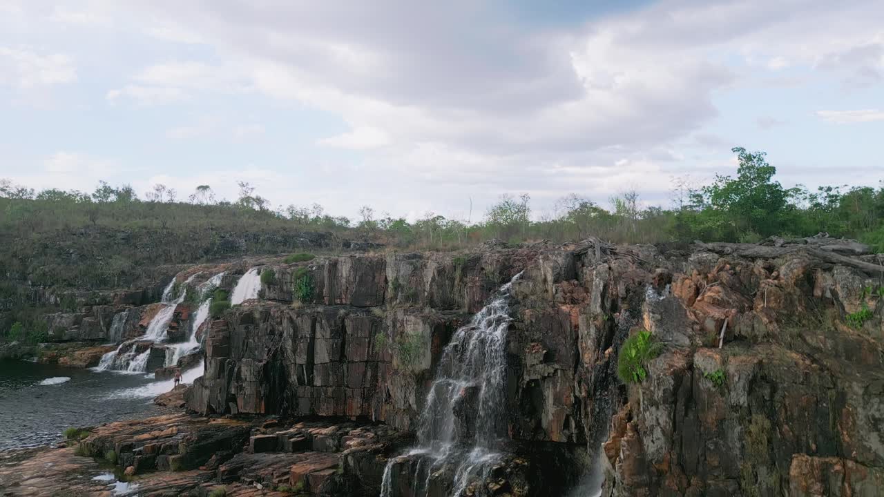 dos couros cae en cascada por una serie de acantilados rocosos en el corazón del parque nacional chapada dos veadeiros, creando un espectáculo natural dinámico y hipnotizante bajo un cielo nublado.