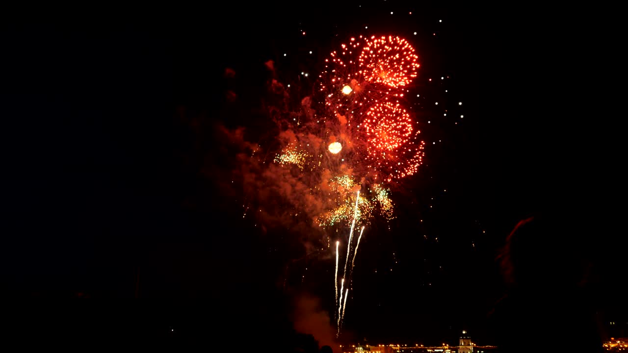 una multitud de personas mira los coloridos fuegos artificiales y celebra.