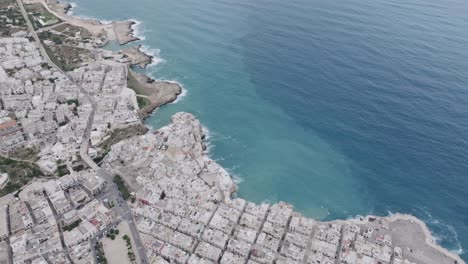 aerial footage above the town of polignano a mare on a cloudy day with a view of the mediterranean sea