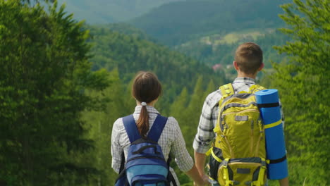 A-Couple-Of-Tourists-With-Backpacks-Enter-The-Frame-Enjoy-The-Beautiful-Mountain-Scenery-Clear-Summe