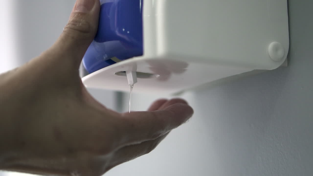 aplicando gel desinfectante de manos en las palmas de las manos, subrayando la importancia de mantener las manos limpias y desinfectadas para la salud y la seguridad